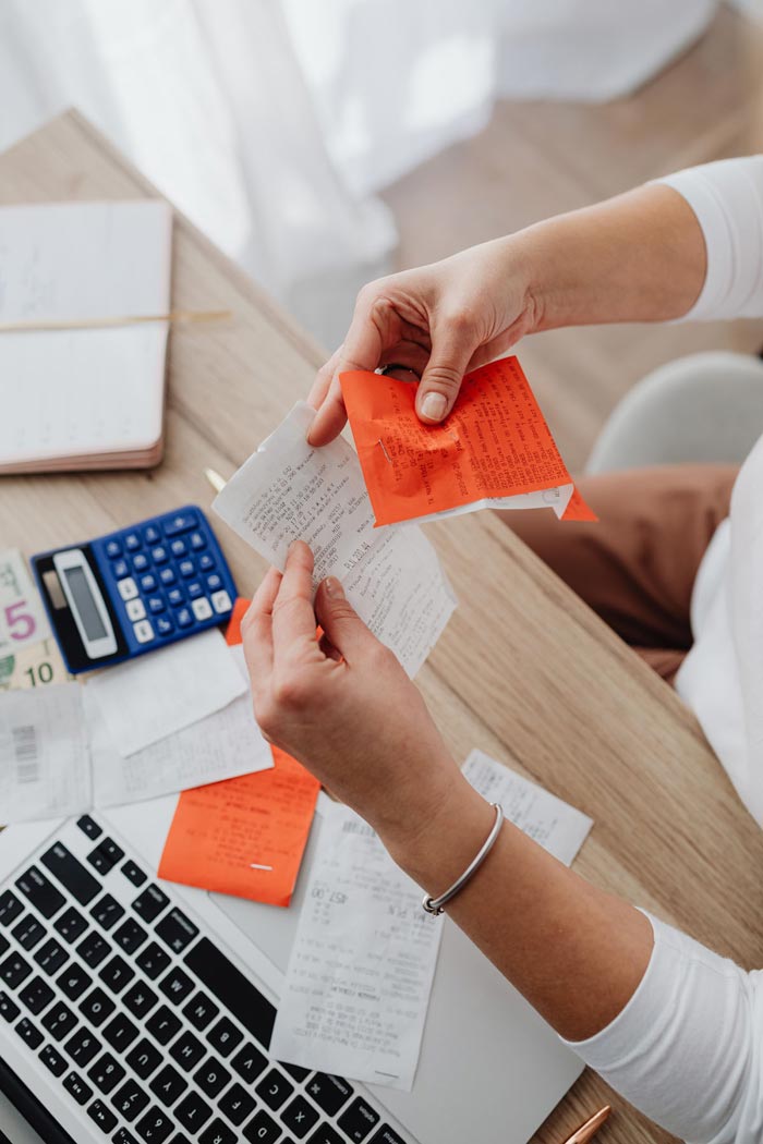 Image of bookkeeper with receipts, bills, calculator wishing they had ABC6 accounts software